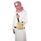 A man in a white thobe and red-checked scarf wearing the beige Hajj bag for men