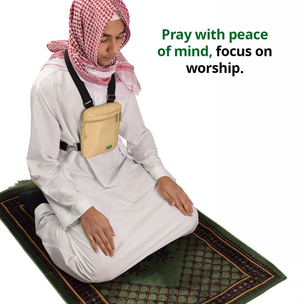 A man kneeling on a prayer mat wearing the beige Hajj bag for men