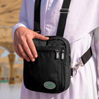 A pilgrim in white holding the black Hajj bag for women on a side strap