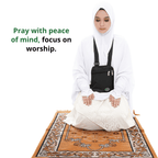 A woman kneeling on a prayer mat wearing the black Hajj bag for women